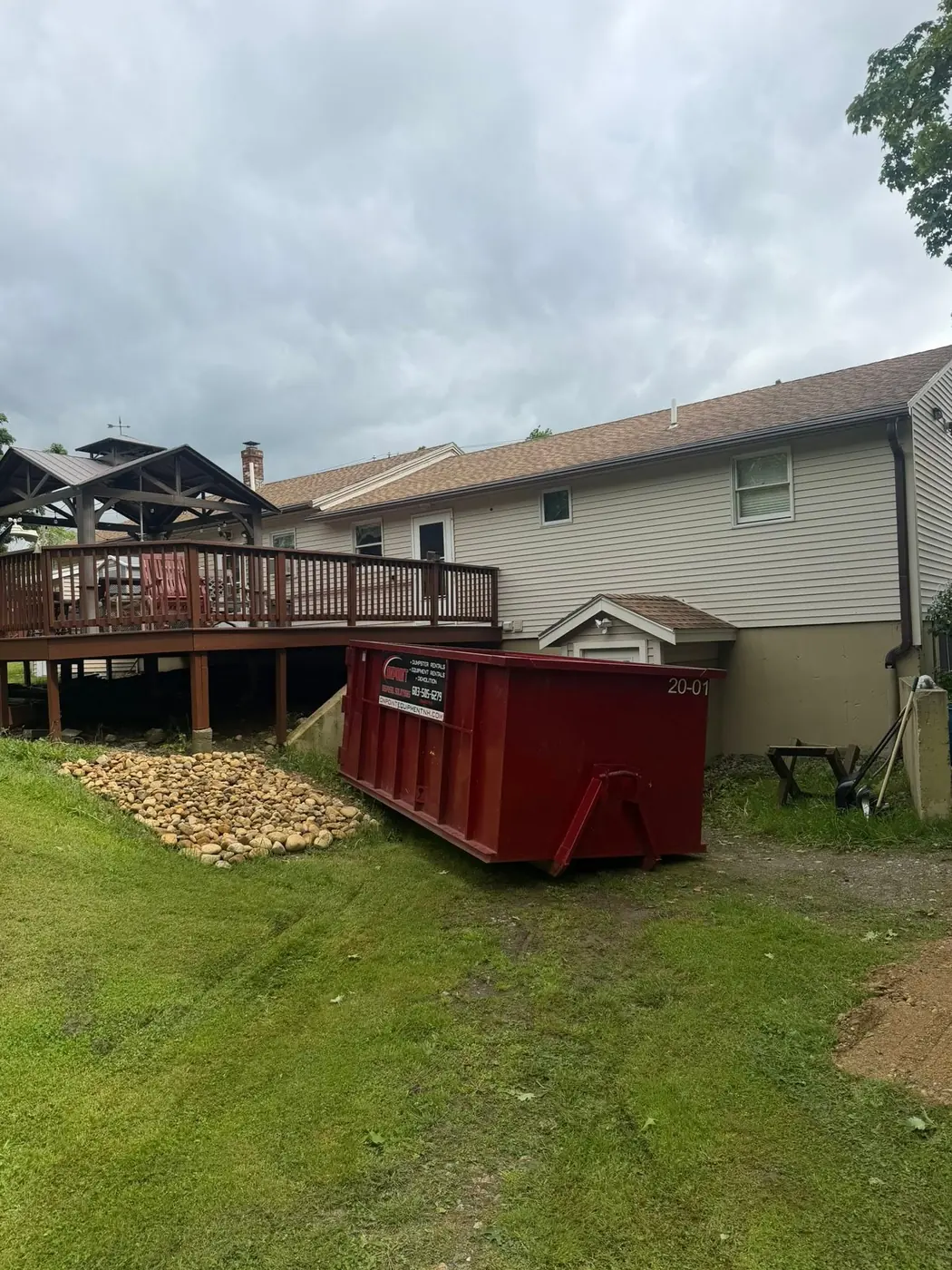Red Onpoint roll off dumpster placed beside a backyard deck for a home renovation