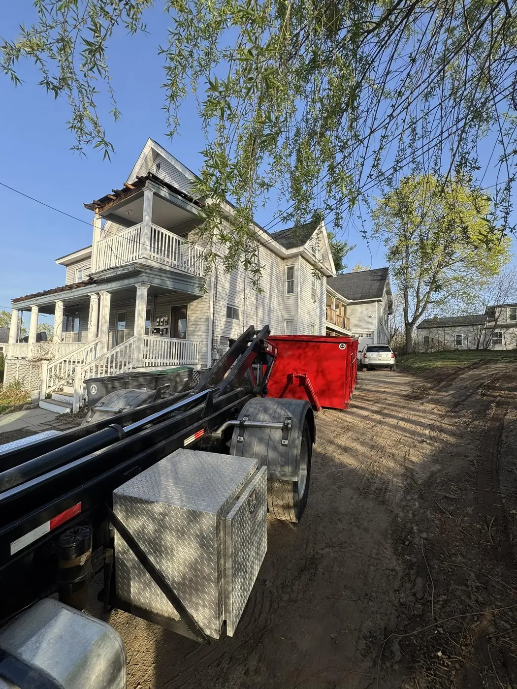 Red roll off dumpster placed beside a multi family home for a cleanout project