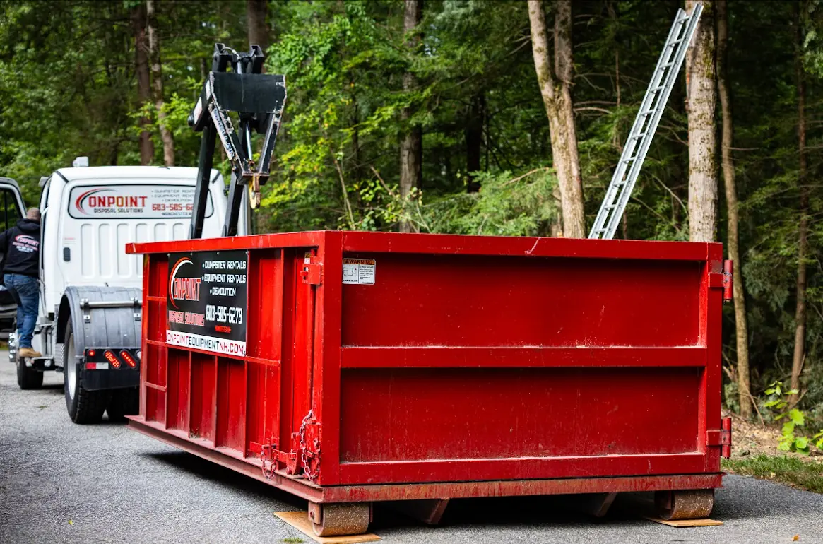 Red Onpoint roll off dumpster set on wooden boards to protect a paved residential driveway