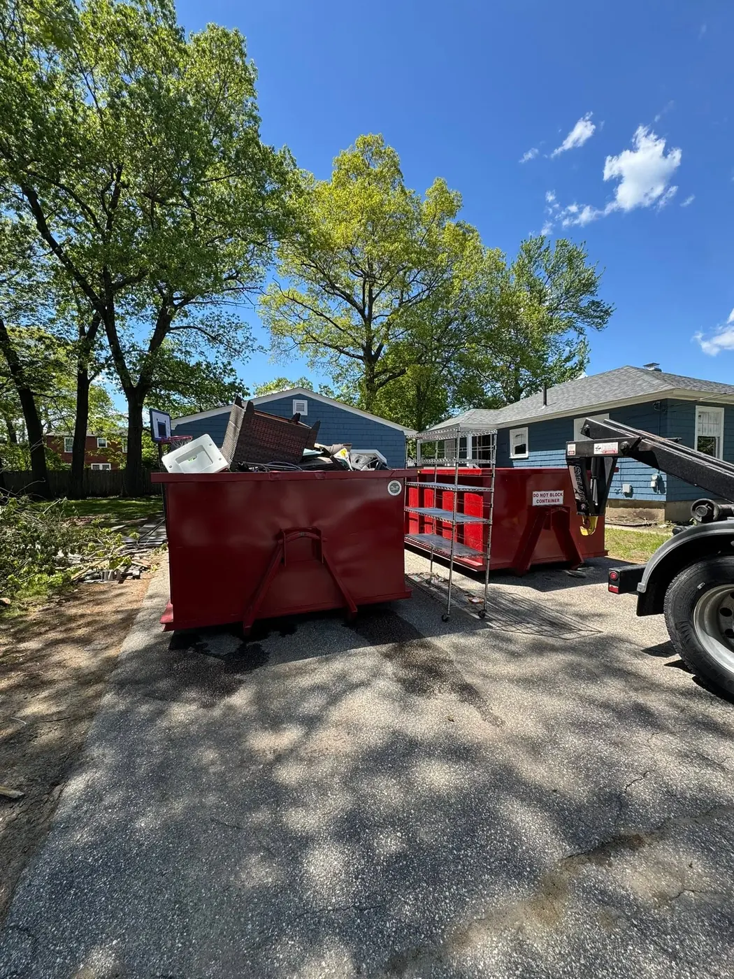 Onpoint roll off dumpsters in a driveway during a household cleanout with furniture loaded