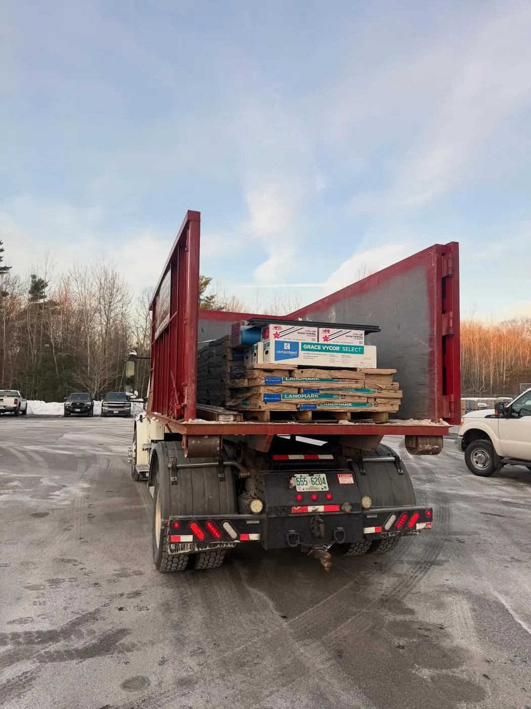 Onpoint roll off truck carrying roofing shingles and underlayment for a contractor job