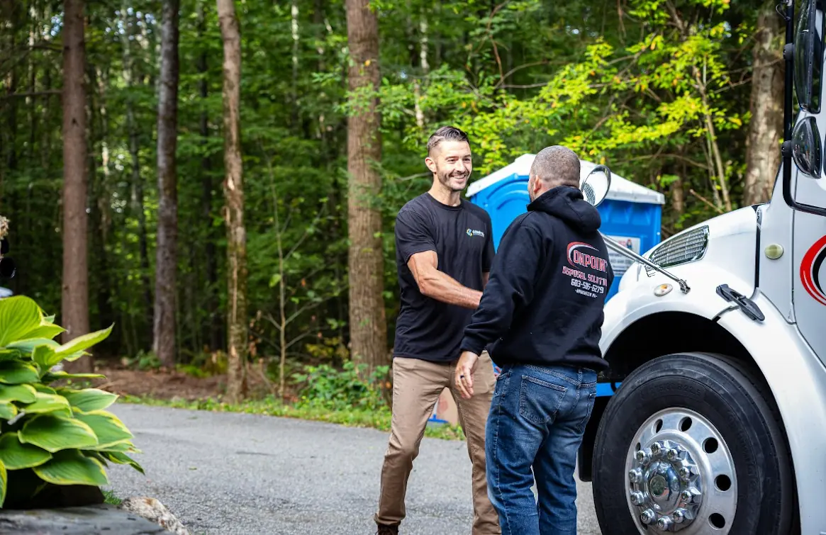 Onpoint Disposal Solutions crew member meeting a customer beside the roll off truck at a job site
